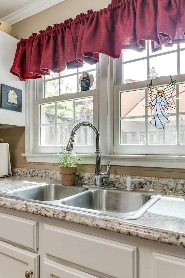 interior details featuring crown molding, white cabinets, a sink, and light countertops