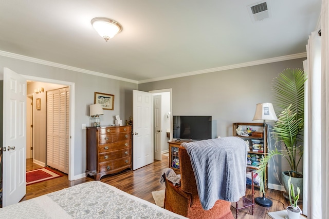 bedroom with ornamental molding, wood finished floors, visible vents, and baseboards