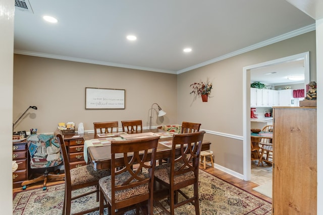 dining space featuring light wood-style flooring, visible vents, and ornamental molding