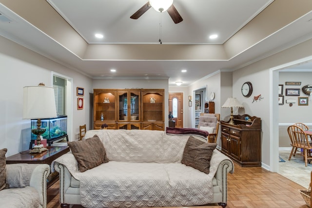 living area with baseboards, a tray ceiling, crown molding, and recessed lighting