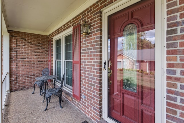 view of exterior entry with covered porch and brick siding