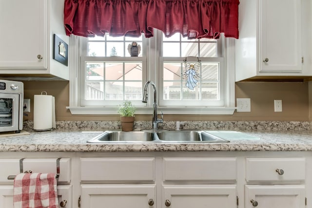 kitchen featuring light countertops, a sink, and white cabinets