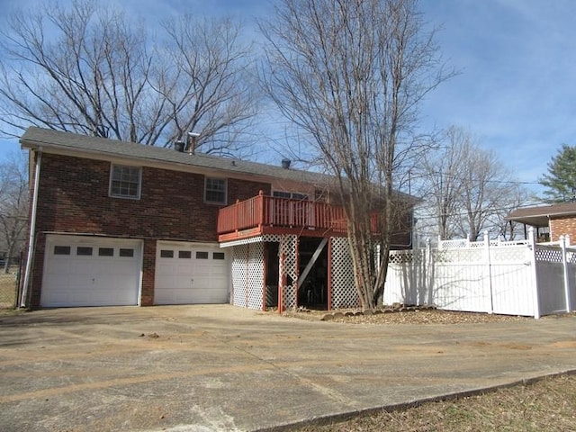 view of front of home featuring concrete driveway, an attached garage, fence, a deck, and brick siding