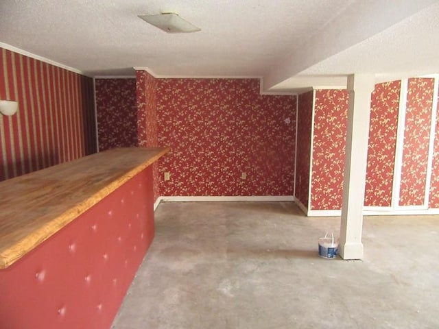 interior space featuring a textured ceiling, baseboards, and wallpapered walls