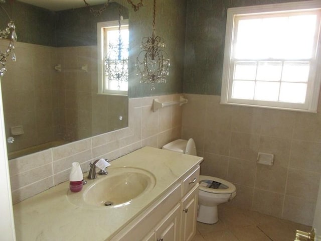 bathroom featuring tile walls, toilet, vanity, tile patterned flooring, and tiled shower