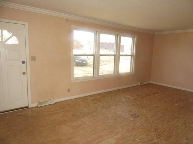 foyer entrance with baseboards, carpet, visible vents, and crown molding