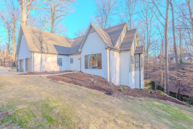 view of front facade featuring a garage, a shingled roof, a front yard, and stucco siding