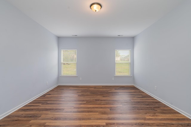 spare room with visible vents, dark wood finished floors, and baseboards