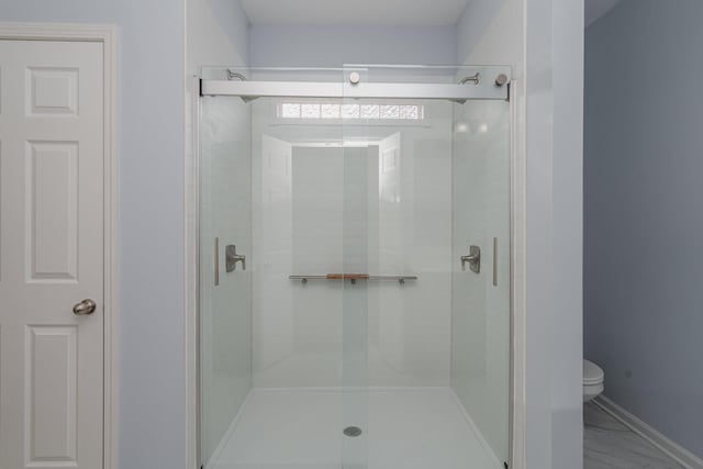 full bath with toilet, marble finish floor, and a shower stall