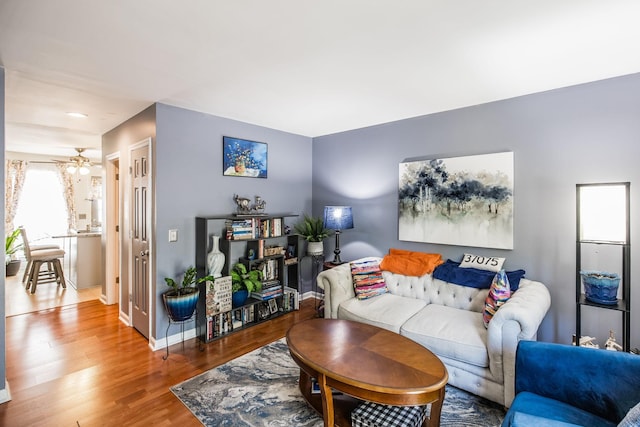 living area with ceiling fan, baseboards, and wood finished floors