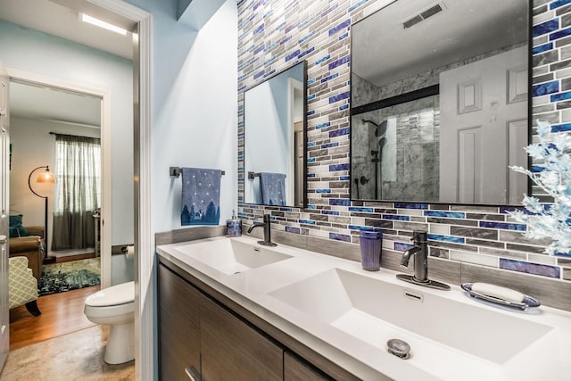 full bath with toilet, a sink, visible vents, and decorative backsplash