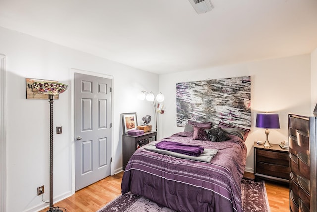 bedroom featuring light wood-style floors, visible vents, and baseboards