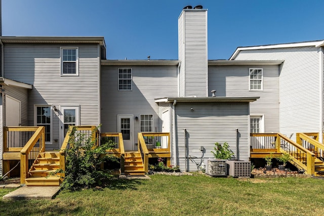 rear view of property featuring a deck, a yard, and a chimney