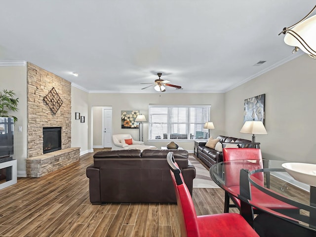 living room featuring ornamental molding, a fireplace, wood finished floors, and visible vents