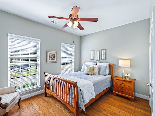 bedroom featuring visible vents, ceiling fan, baseboards, and wood finished floors