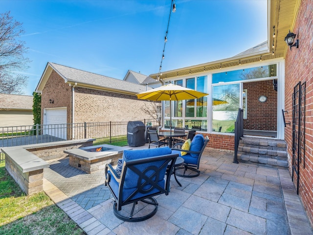 view of patio featuring a garage, fence, a fire pit, and grilling area