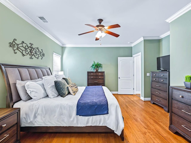 bedroom featuring visible vents, crown molding, light wood-style flooring, and baseboards