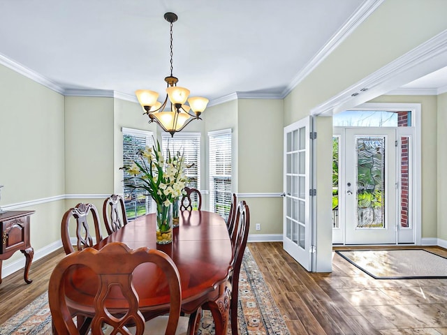 dining area with an inviting chandelier, baseboards, ornamental molding, and wood finished floors