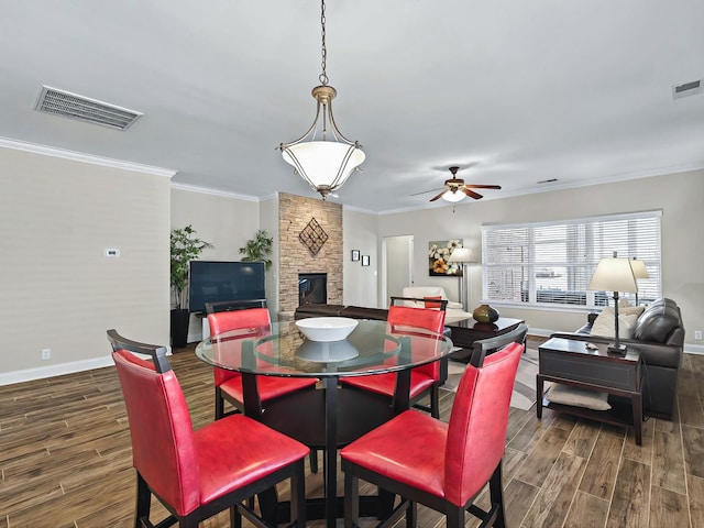 dining space with visible vents, dark wood finished floors, and a stone fireplace