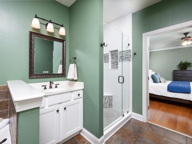 ensuite bathroom with baseboards, connected bathroom, ceiling fan, vanity, and a shower stall