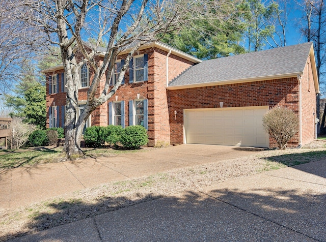 colonial house with a garage, concrete driveway, brick siding, and a shingled roof