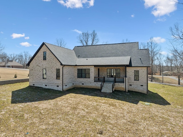 rear view of house featuring roof with shingles, brick siding, crawl space, and a lawn