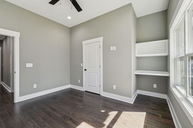 empty room with dark wood-style floors, ceiling fan, and baseboards