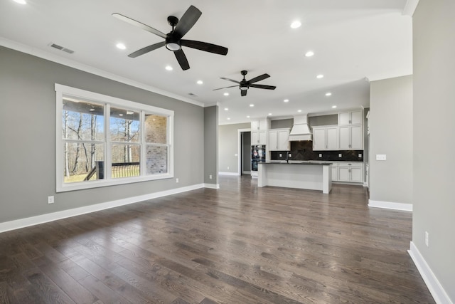 unfurnished living room with baseboards, dark wood-type flooring, and crown molding