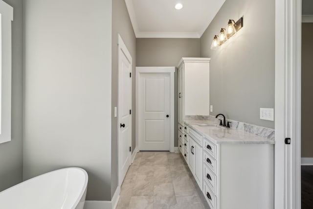 full bath featuring crown molding, a freestanding bath, vanity, and baseboards