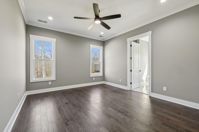 empty room with a wealth of natural light, dark wood-style flooring, visible vents, and baseboards