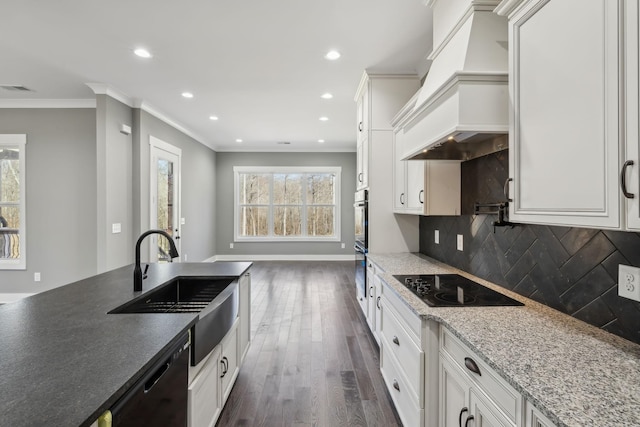 kitchen featuring premium range hood, dark wood-style flooring, a sink, decorative backsplash, and black appliances