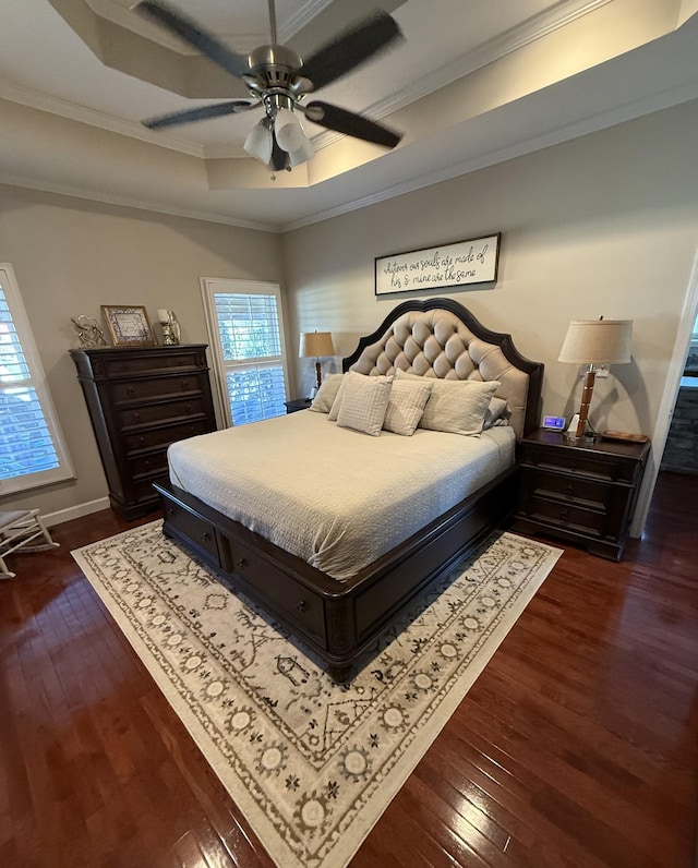 bedroom featuring a raised ceiling, crown molding, and dark wood-style floors