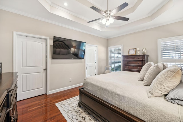 bedroom with baseboards, a raised ceiling, dark wood-type flooring, and ornamental molding