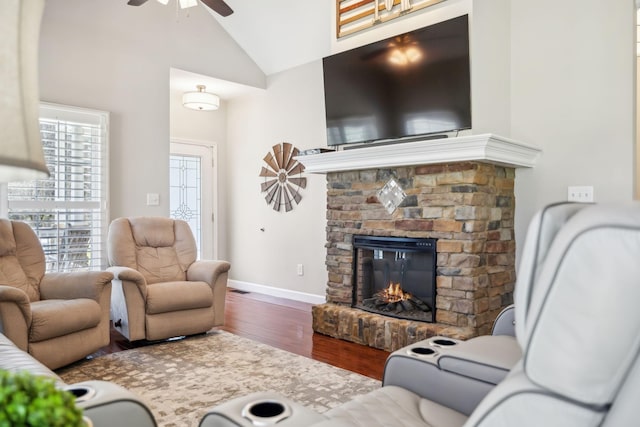 living room with baseboards, lofted ceiling, a fireplace, wood finished floors, and a ceiling fan