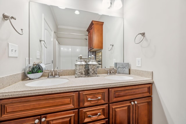 full bath with a sink, walk in shower, double vanity, and crown molding