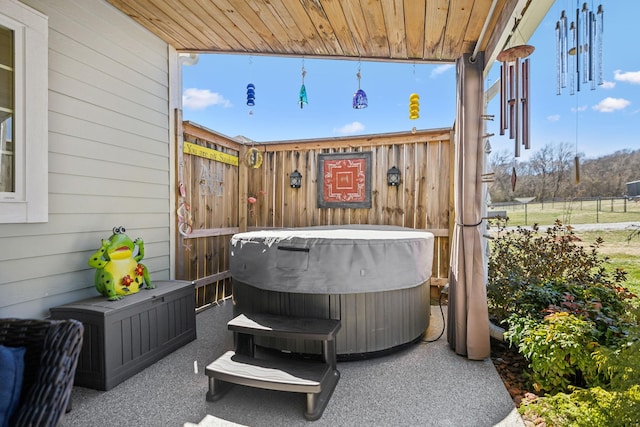 view of patio with a hot tub and fence