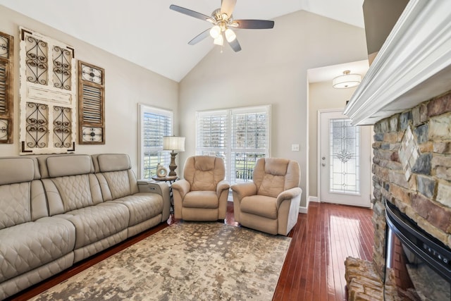 living area with a stone fireplace, high vaulted ceiling, a ceiling fan, and wood finished floors