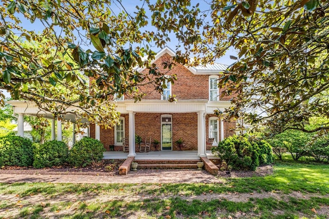 view of front of home with a porch, a front lawn, and brick siding