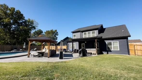 rear view of property with a fenced backyard, a gazebo, a lawn, a fenced in pool, and a patio area