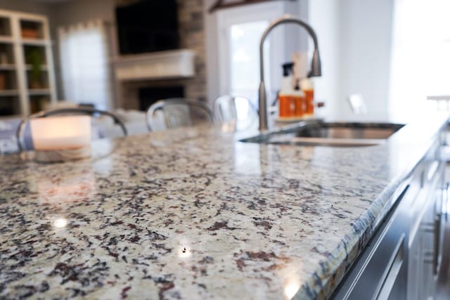 details with a fireplace, a sink, and light stone countertops