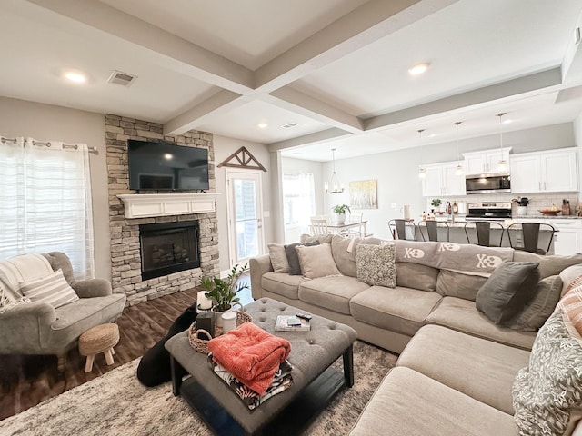 living area featuring dark wood-style floors, recessed lighting, visible vents, a stone fireplace, and beamed ceiling