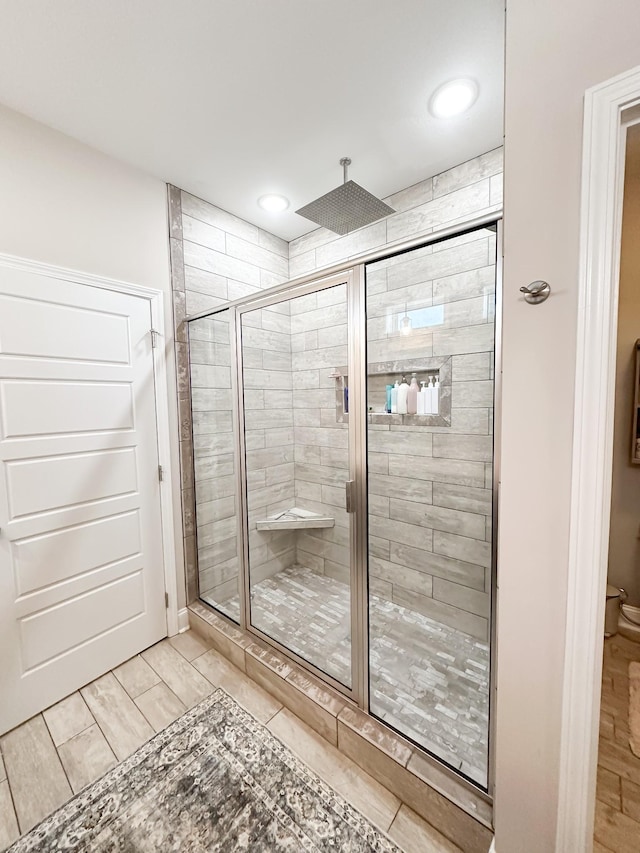 full bath featuring toilet, a shower stall, and wood tiled floor