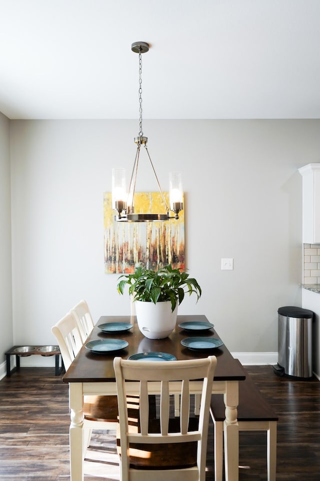 unfurnished dining area featuring dark wood-style floors, a notable chandelier, and baseboards