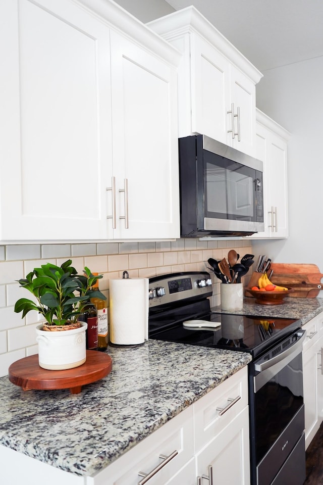 kitchen with appliances with stainless steel finishes, white cabinets, and backsplash