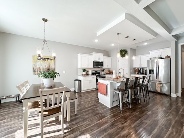 kitchen with appliances with stainless steel finishes, dark wood-style flooring, a breakfast bar area, and an island with sink