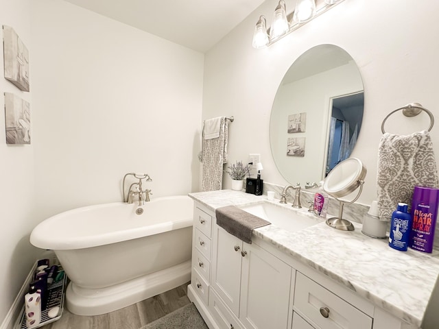 full bath with a freestanding tub, vanity, and wood finished floors