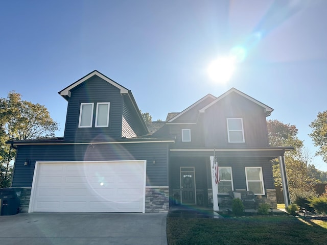 view of front of property with a garage, covered porch, stone siding, and concrete driveway