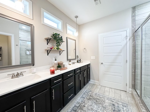 full bath with double vanity, a shower stall, visible vents, and a sink