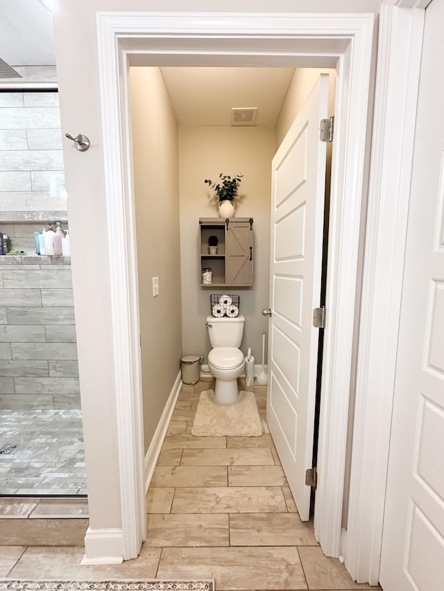 bathroom featuring toilet, visible vents, baseboards, a shower stall, and wood tiled floor