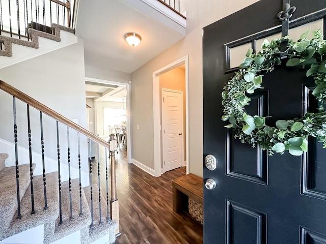 entryway with a towering ceiling, stairway, baseboards, and wood finished floors